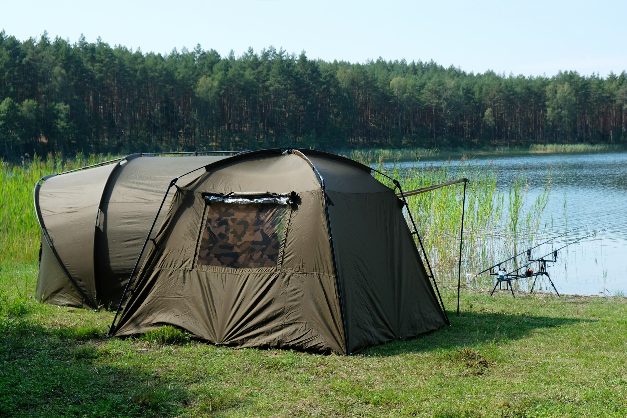 The anglers' tents stand by the lake. There are two fishing rods Das Angelzelt Mit der richtigen Pflege ein treuer Begleiter Angel Wissen – Bild 1
